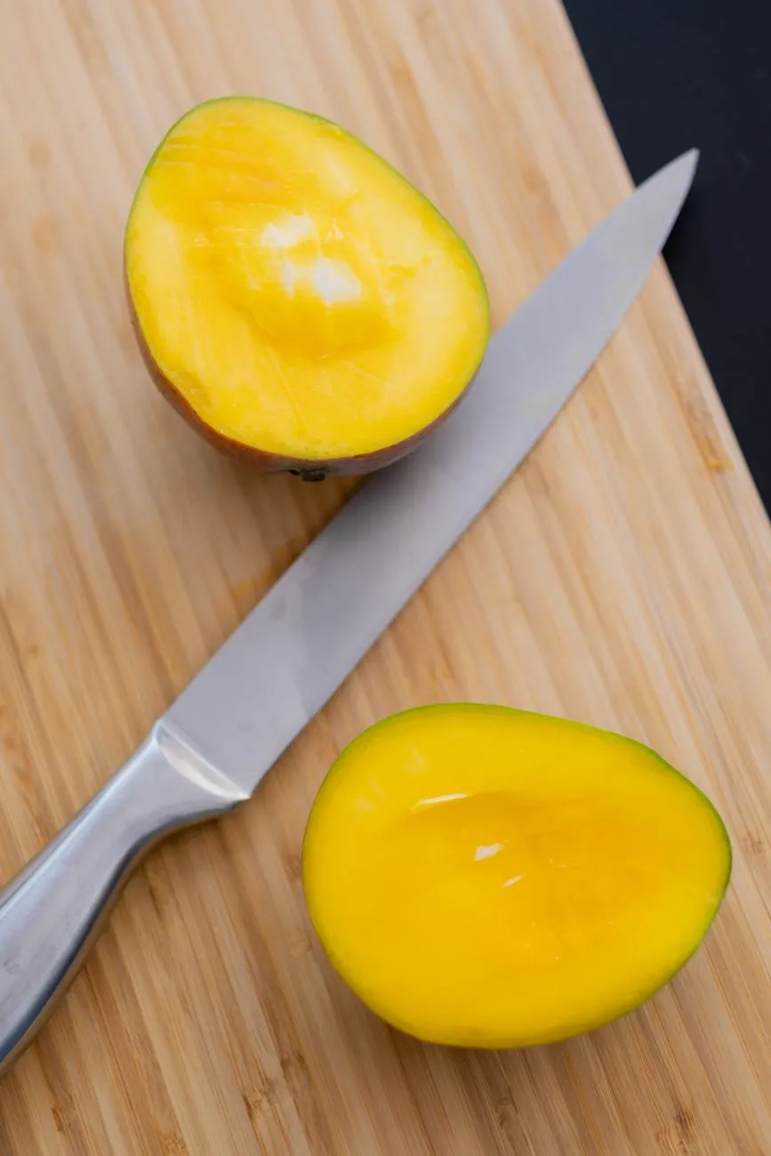 Mangue coupée en deux moitiés sur une planche en bois, laissant voir le noyau central